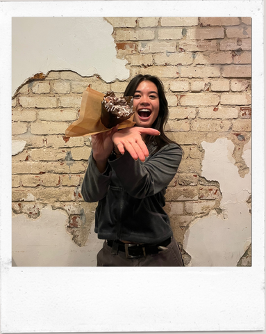 Barista against a brick wall holding a monkey bread muffin