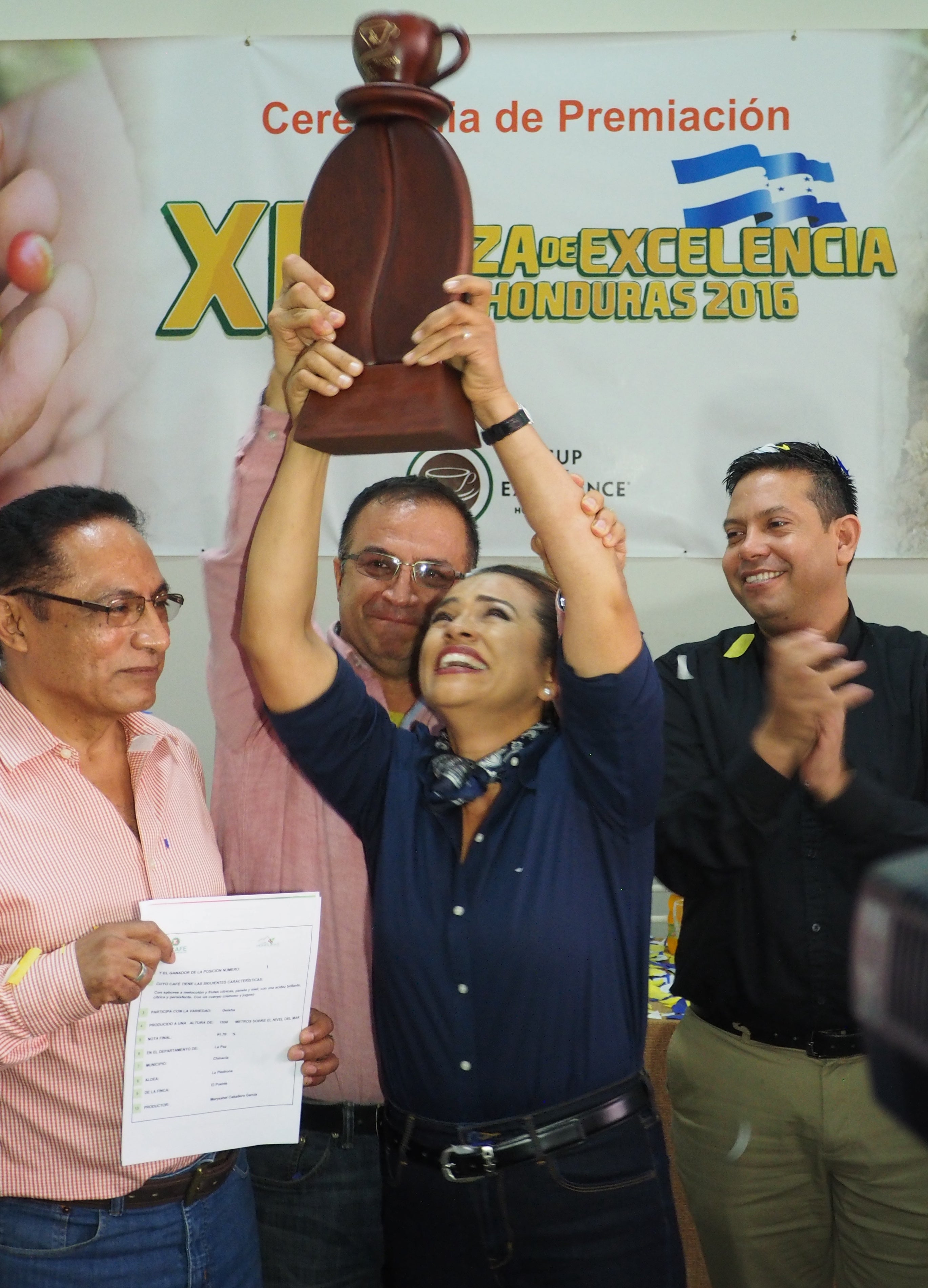 COMSA producer Marysabel Caballero Garcia holding up the trophy for winning the 2016 Cup of Excellence