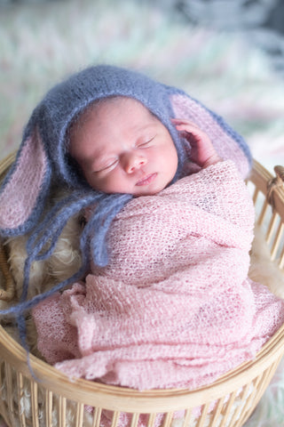 baby in a basket wrapped in a pink blanket