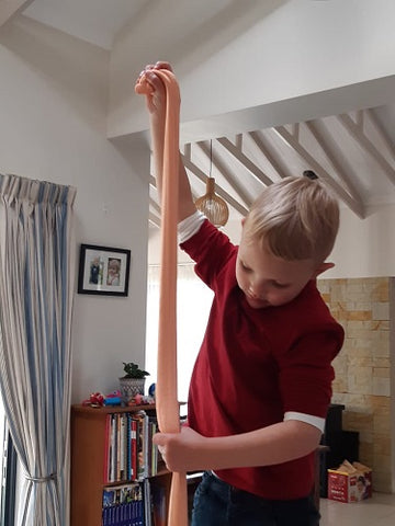 boy stretching orange magic sand vertically