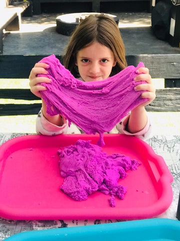 girl sitting outside stretching purple magic sand