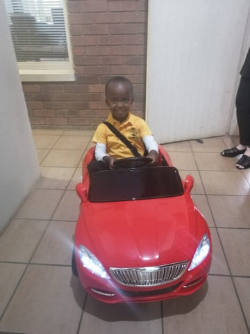 Boy sitting and riding in his red electric toy car