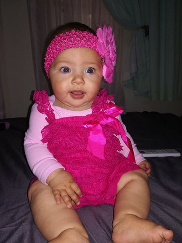 girl wearing a hot pink lace romper with large daisy headband