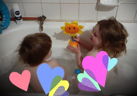 toddlers playing with the sunflower bath toy in the bath