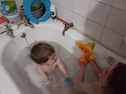 aerial shot of toddlers playing in  the bath with the sunflower bath toy