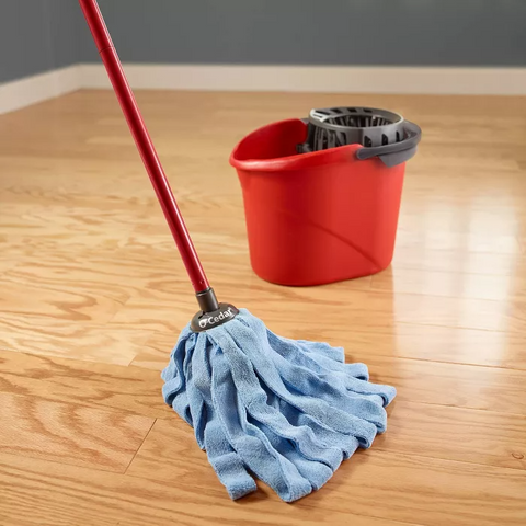 Blue mop and red mopping pail on wood flooring