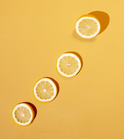Four slices of lemon against yellow background