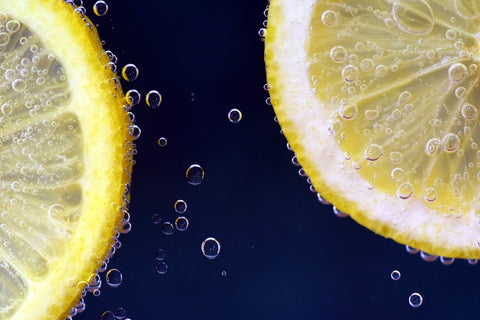 Two slices of lemon with bubbles against dark blue background