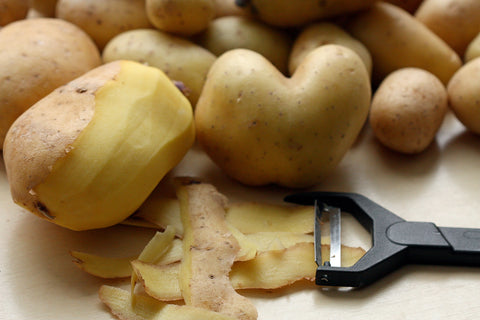 Half-peeled potato among many potatoes