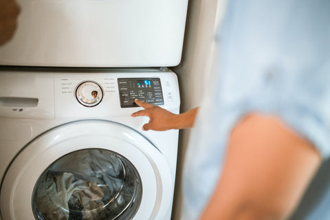 Person pressing a button on a washing machine