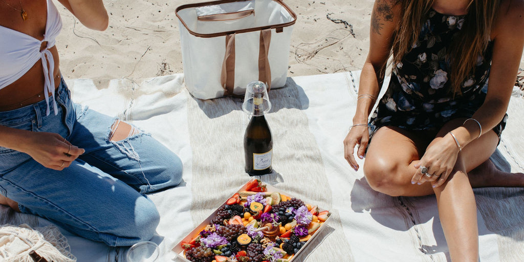 Two young ladies having a beach picnic with a colorful charcuterie board