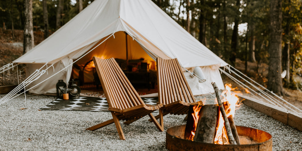 Outdoor wood folding chairs in front of a tent with a firepit 