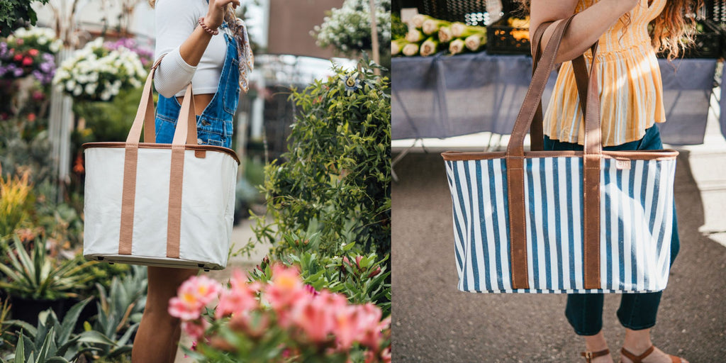 Woman (left) wearing short overalls holding cream colored collapsible LUXE tote and surrounded by plants. Girl (right) in yellow shirt and jeans holding navy striped collapsible luxe tote at farmer's market