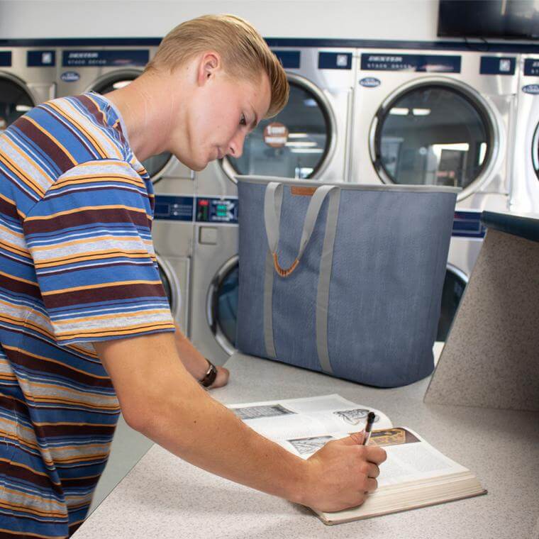 college student at the laundrymat with a Laundry Caddy LUXE