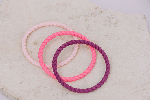 three pink and purple silicone rope bracelets