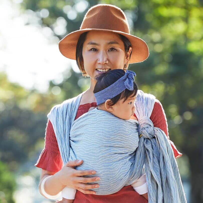 短いベビーラップで赤ちゃんを対面で抱っこする女性