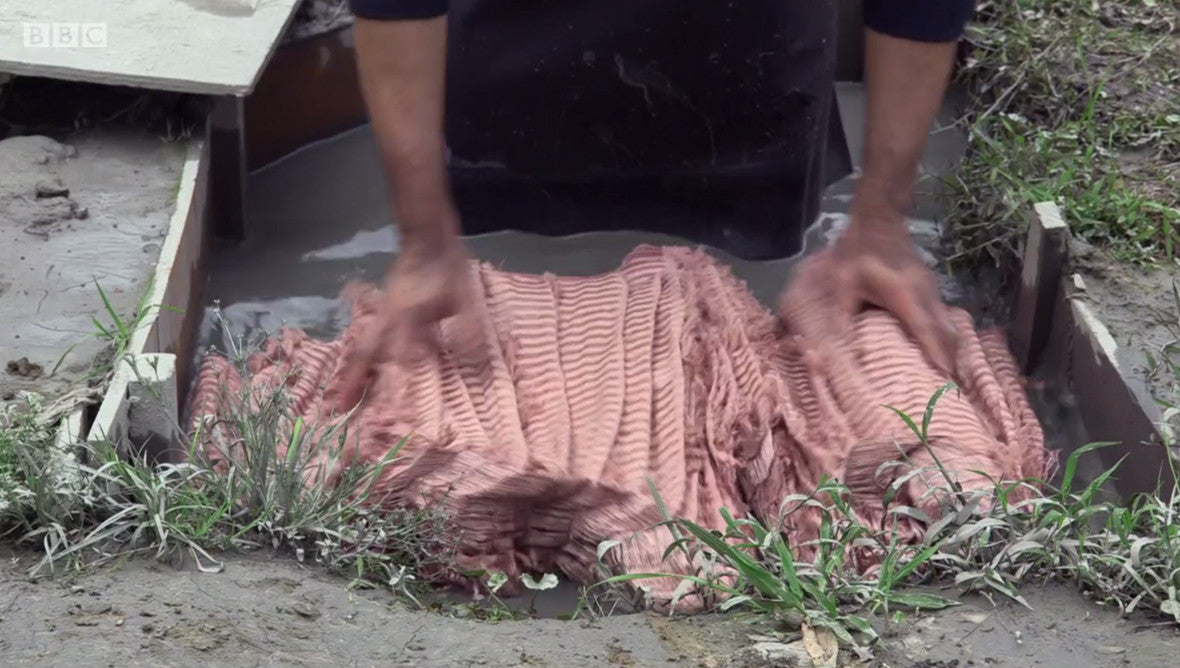 Wood dyed silk being dyed black with river mud