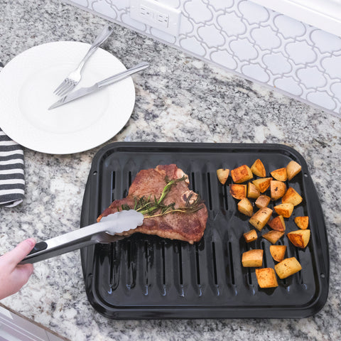 Steak and potatoes being removed from Certified Appliance Accessories broiler pan