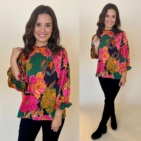 abstract floral print top in black, pink, orange and green. paired with black jeans and black boots