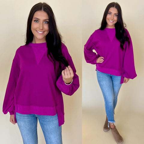 purple oversized sweatshirt with puff sleeves. sweatshirt is paired with light denim jeans and tan boots