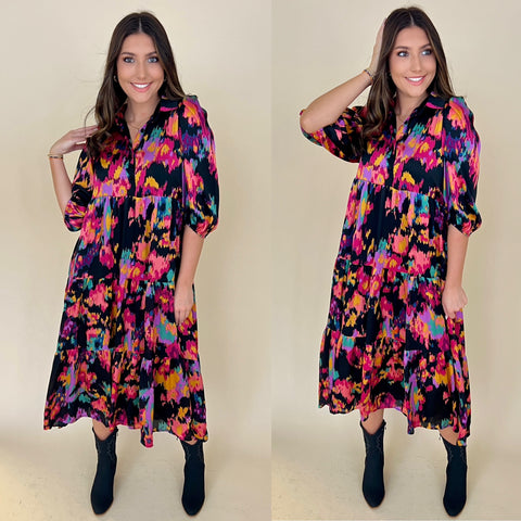 black abstract print maxi dress with pink, blue and purple on it. Dress is a collared button up style with puff sleeves. dress is styled with black cowboy boots