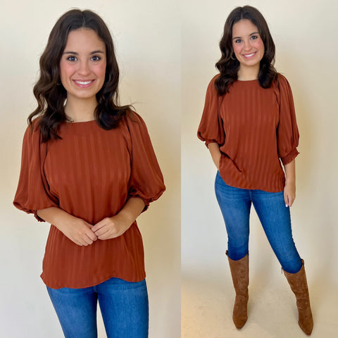 rust colored satin top paired with dark skinny jeans and tall brown cowboy boots
