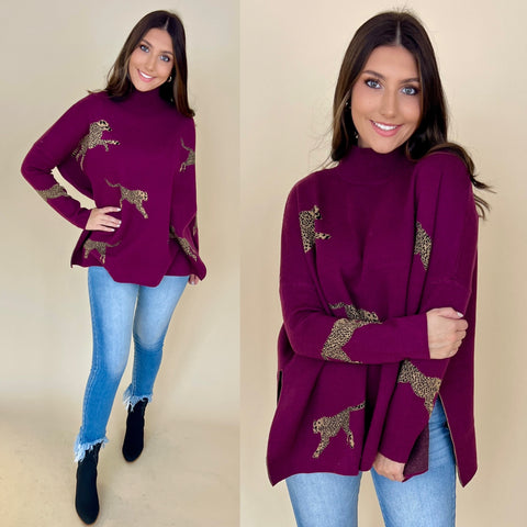 plum colored sweater with cheetahs printed on it. sweater is a long sleeve turtleneck style. It is paired with light denim jeans and black boots