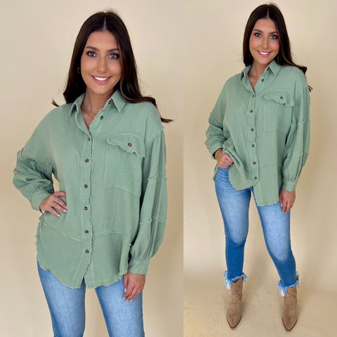 green gauze button down top paired with light denim jeans and boots