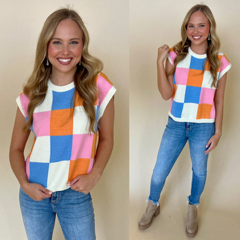 pink, orange and blue checkered print sweater vest paired with light denim jeans and boots