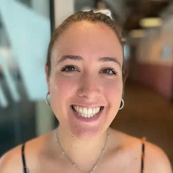 A person smiling indoors with a blurred background.