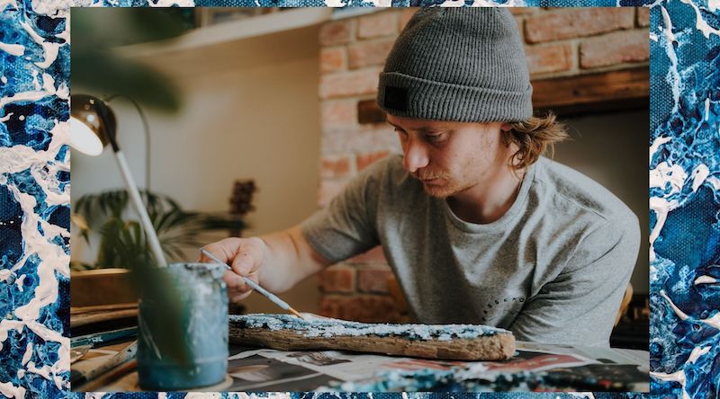 Josh Hibberd artist sat at his desk painting with oil paints