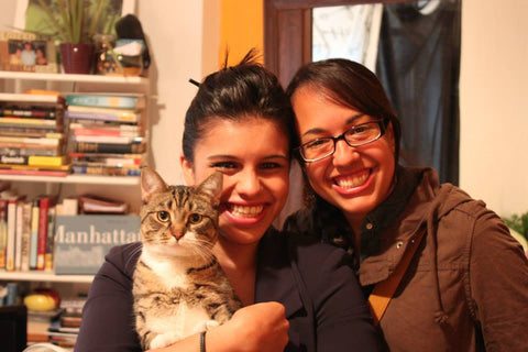 Two friends and their cat chairman meow smiling for the photo