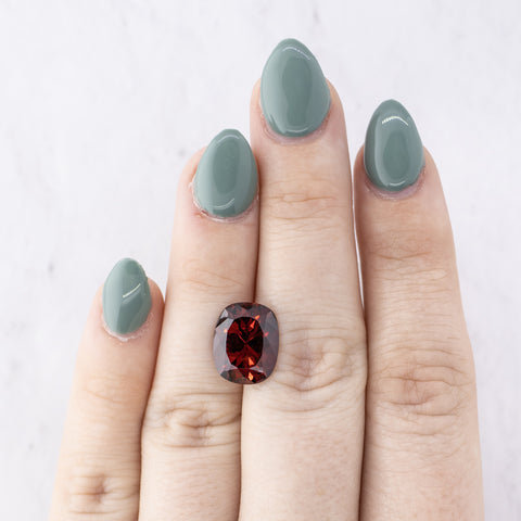 Oval Deep Red Spinel resting on the back of a persons hand