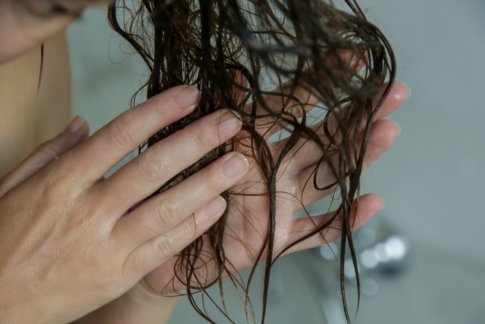 Close up woman applying conditioner to her hair