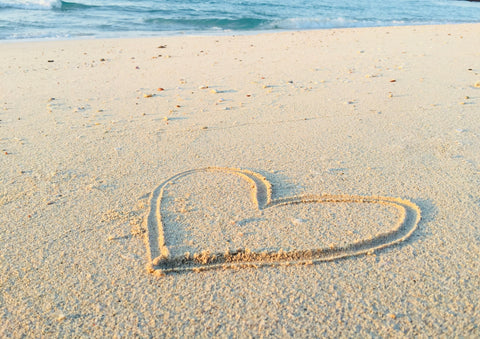 Heart drawn into the sand with ocean in background