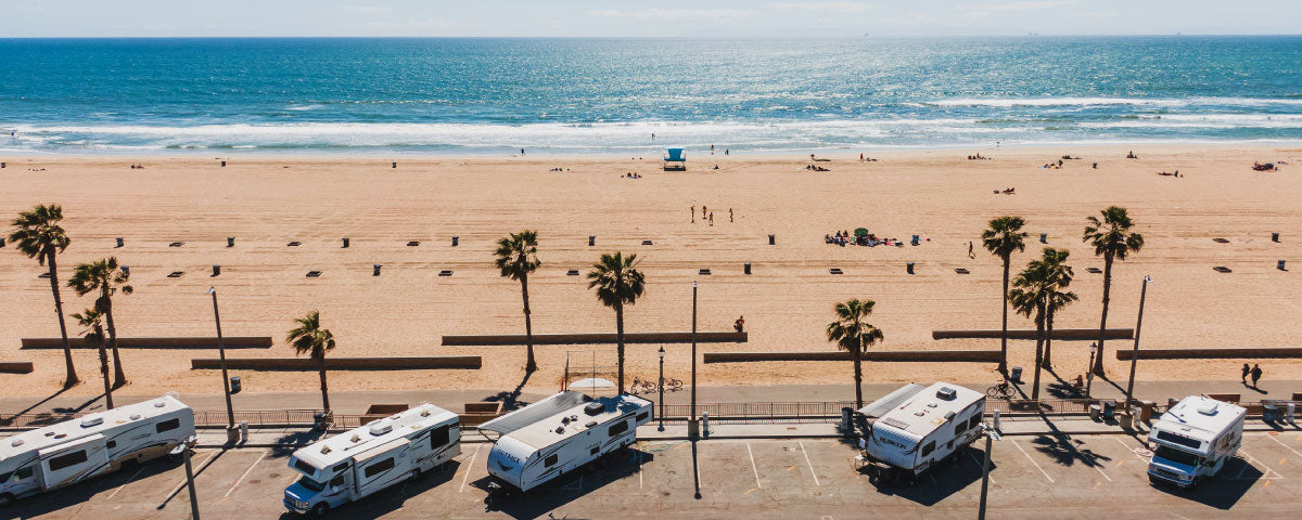 rv trailers campers parked sideways in a parking lot by the pacific ocean