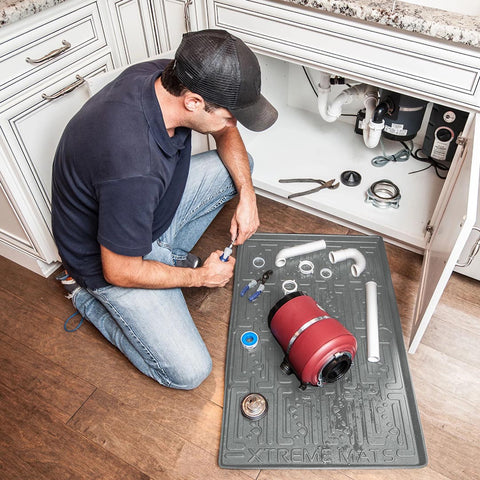 Man using under sink mat while performing sink repairs