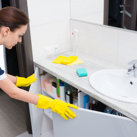 woman opening cabinet under sink