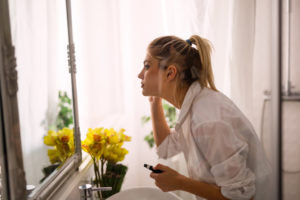 Woman applying makeup while wearing jewellery