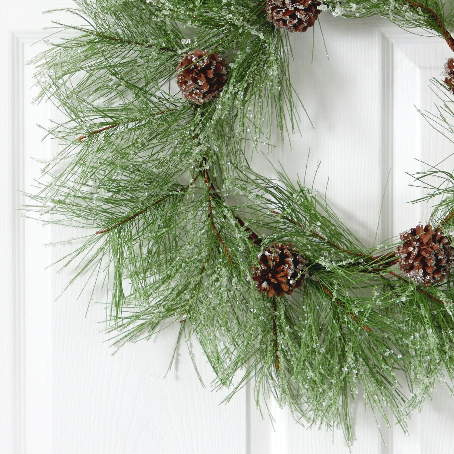 Frosted pine cones sprinkled atop a round evergreen wreath on burlap