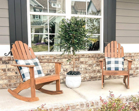 Two beach chairs made out of wood with a pillow, between them is a tall artificial tree from Nearly Natural