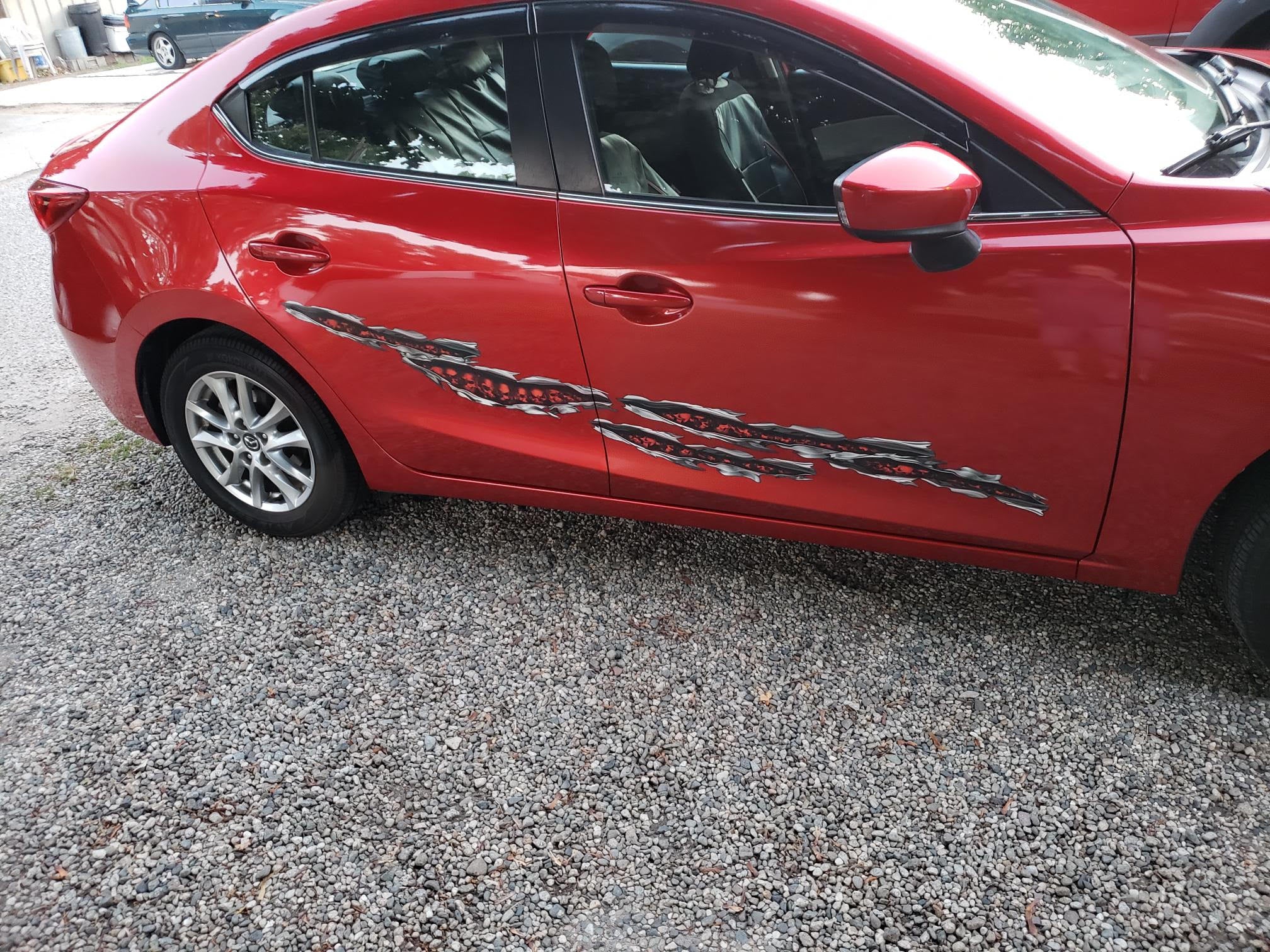 Skulls ripped metal vinyl graphic decal on side of red car