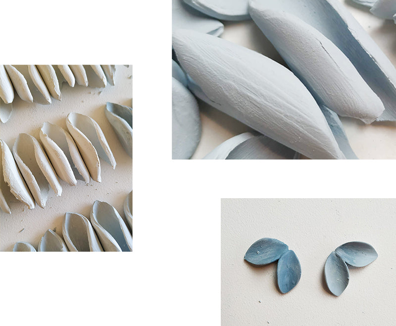Blue raw porcelain pieces arranged on a table in a studio, showcasing their unique shapes and shades of blue, representing artistic work in progress.