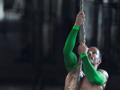 Man wearing Bauerfeind Arm Compression Sleeves as he climbs a rope