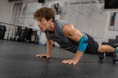 Man at the gym doing push-ups in Bauerfeind's Sports Elbow Support brace