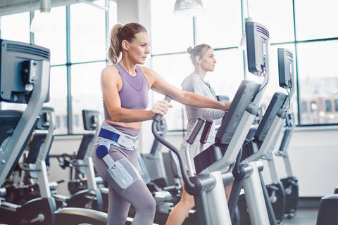 Two women at the gym on treadmills. One is wearing the CoxaTrain Hip Support to manage hip pain