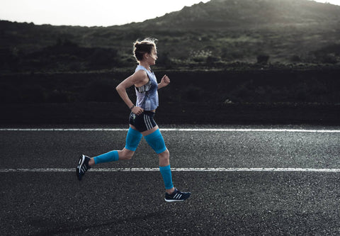 Woman running on an empty road early in the morning. She has good running form, key to avoiding back pain during a run