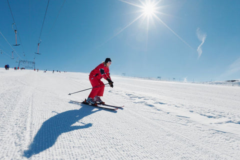 Skier in orange gear practicing good ski form on the slopes, good practice for beginners 