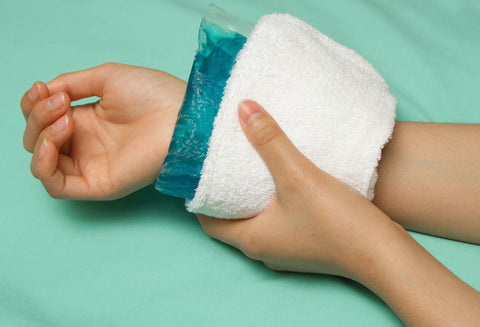 Person folding a green ice pack around their wrist to manage pain and swelling, common symptoms of carpal tunnel syndrome