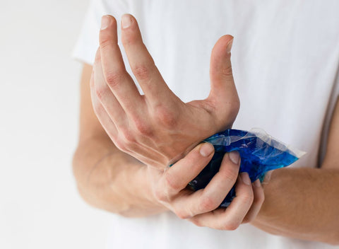 Man applying an ice pack to his injured wrist. The shot focuses on his hands.